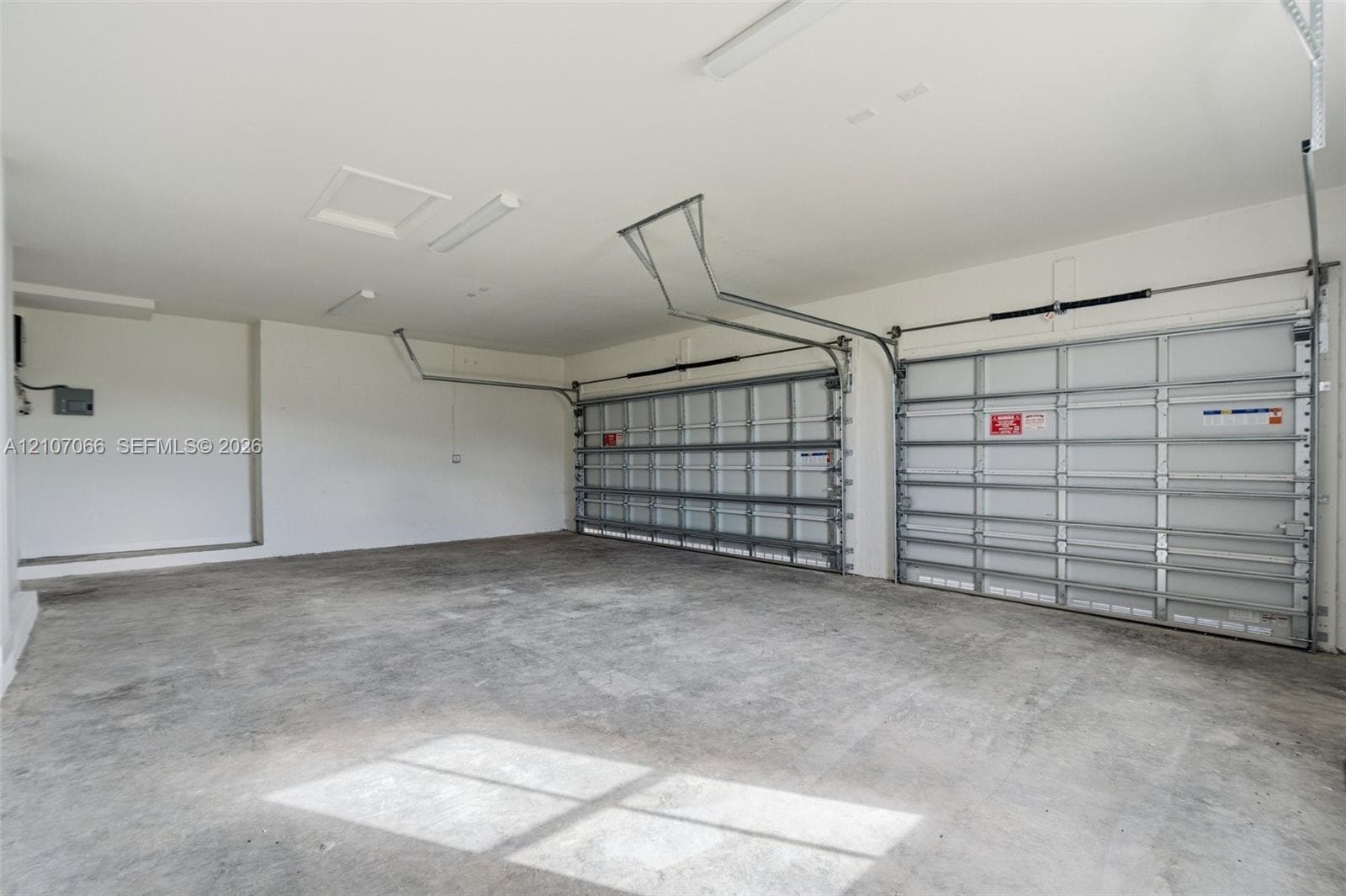 Multi-car garage featuring a concrete floor, high ceilings, and dual overhead doors with integrated automatic openers