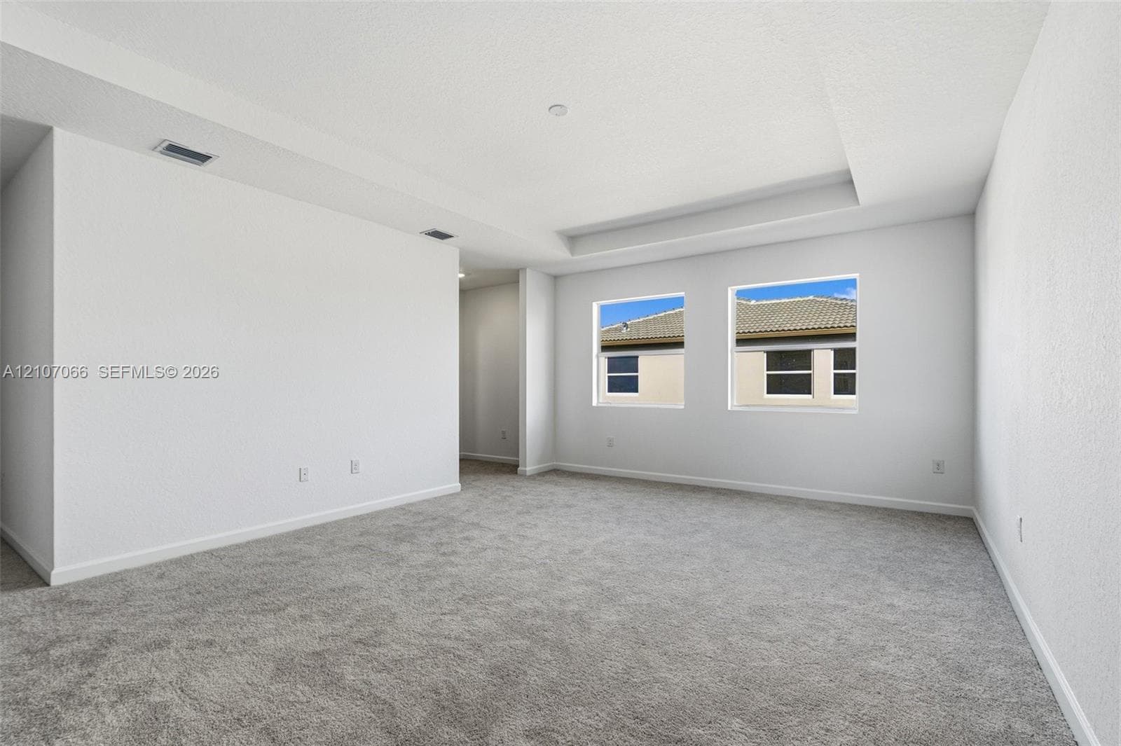 Room featuring a tray ceiling, neutral wall tones, and wall-to-wall carpeting