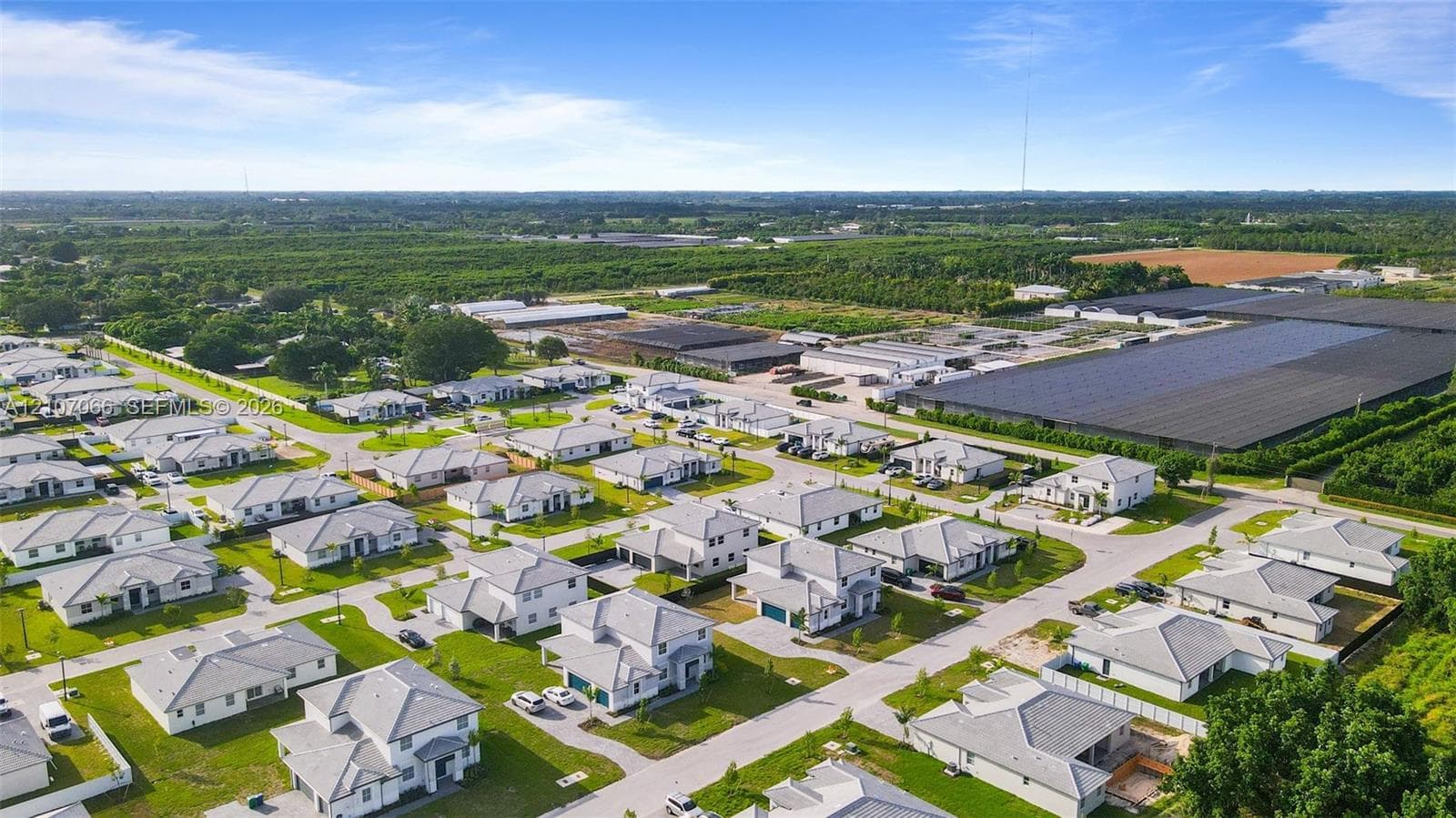 Aerial perspective of a residential neighborhood featuring single-family homes with pitched roofs, paved roads, and manicured lawns