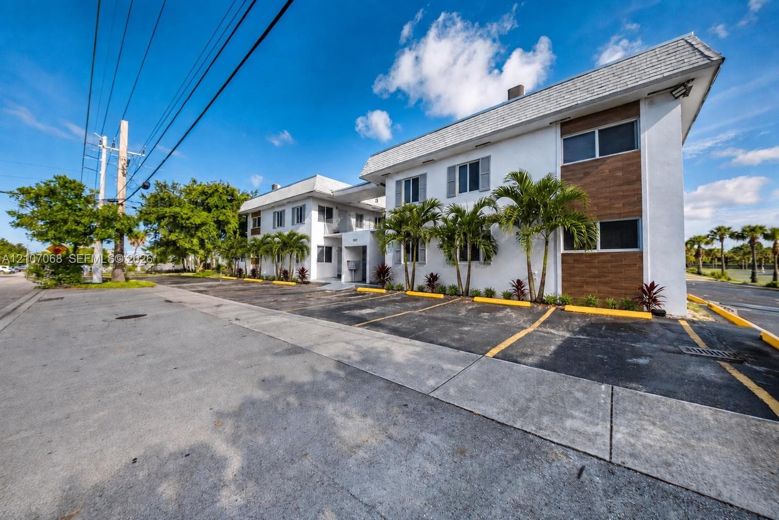 Multi-unit exterior featuring a smooth stucco facade, horizontal wood-finish siding accents, and a shingled roof