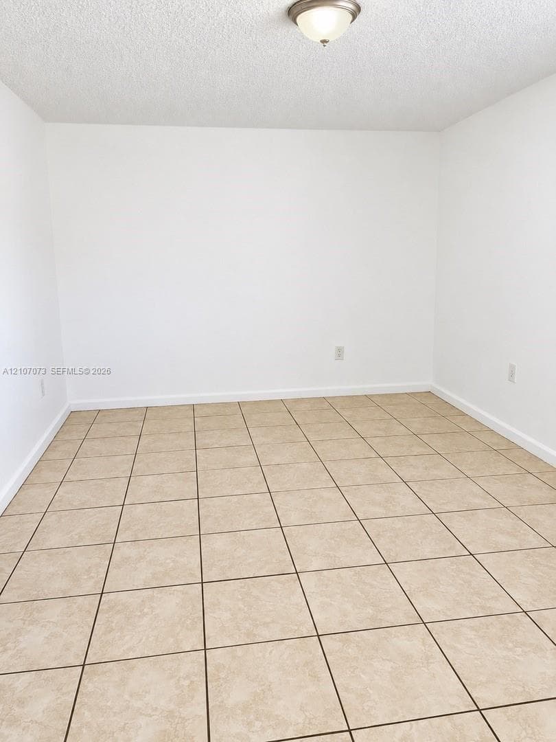 Neutral-toned interior space featuring ceramic tile flooring, crisp white walls, and a ceiling-mounted flush mount light fixture