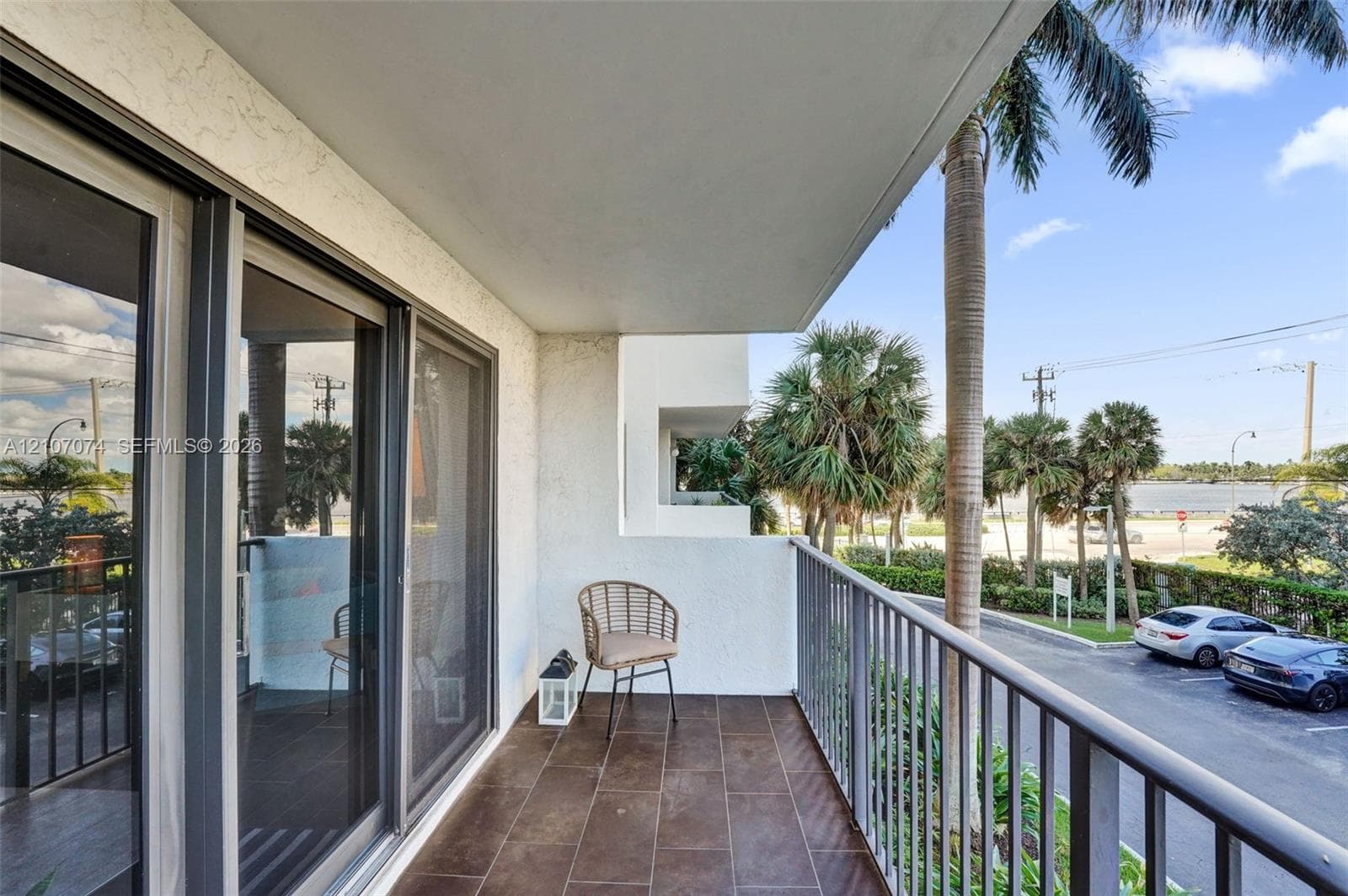 Covered balcony featuring tile flooring, metal railings, and sliding glass door access