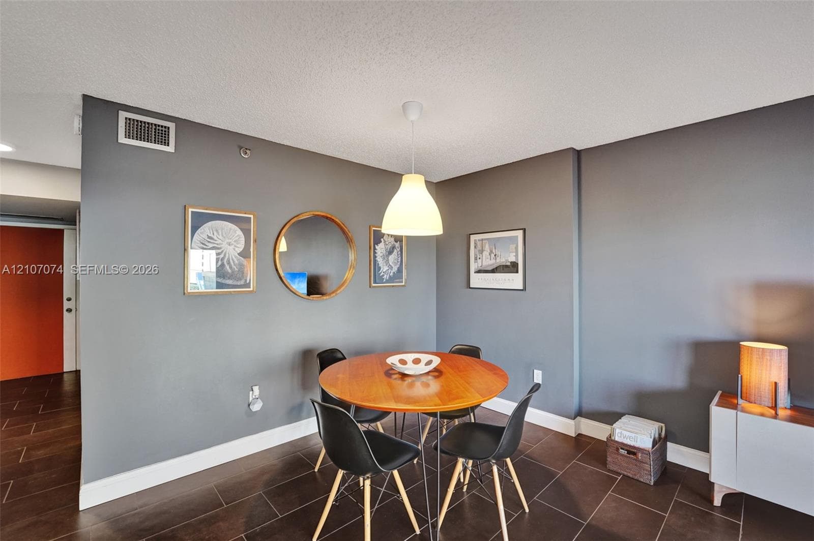 Interior space featuring charcoal-toned walls, large-format tile flooring, and a suspended white pendant light fixture