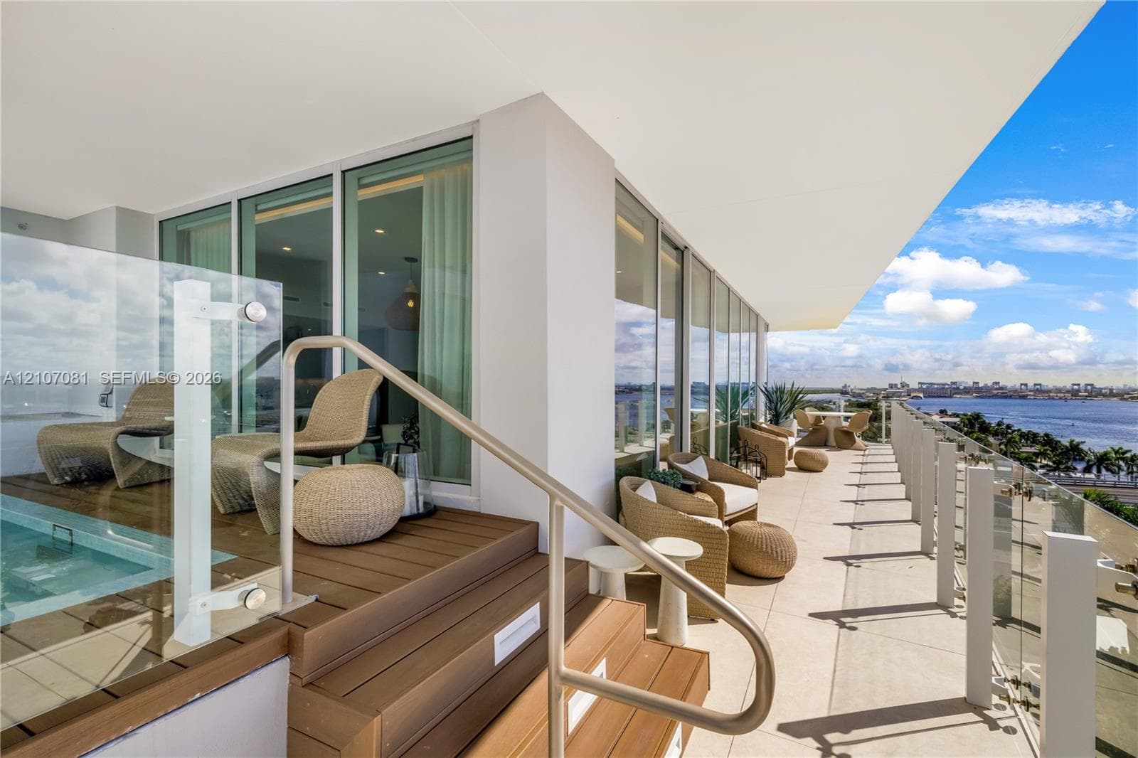 Expansive terrace featuring a raised wood-finish deck, a built-in plunge pool, floor-to-ceiling glass wall panels, a glass railing system, and metal handrails