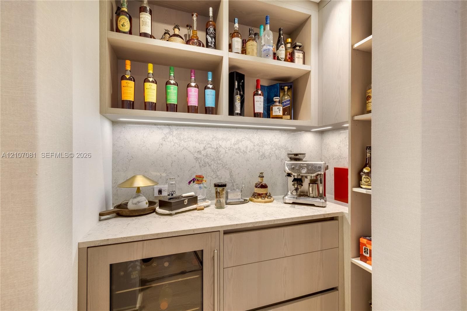 Custom built-in cabinetry with integrated lighting, stone-surface countertop, stone backsplash, and built-in under-counter beverage refrigerator