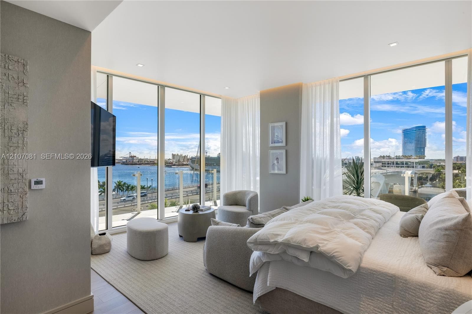 Floor-to-ceiling windows, neutral carpeting, recessed lighting, and a glass-paneled balcony