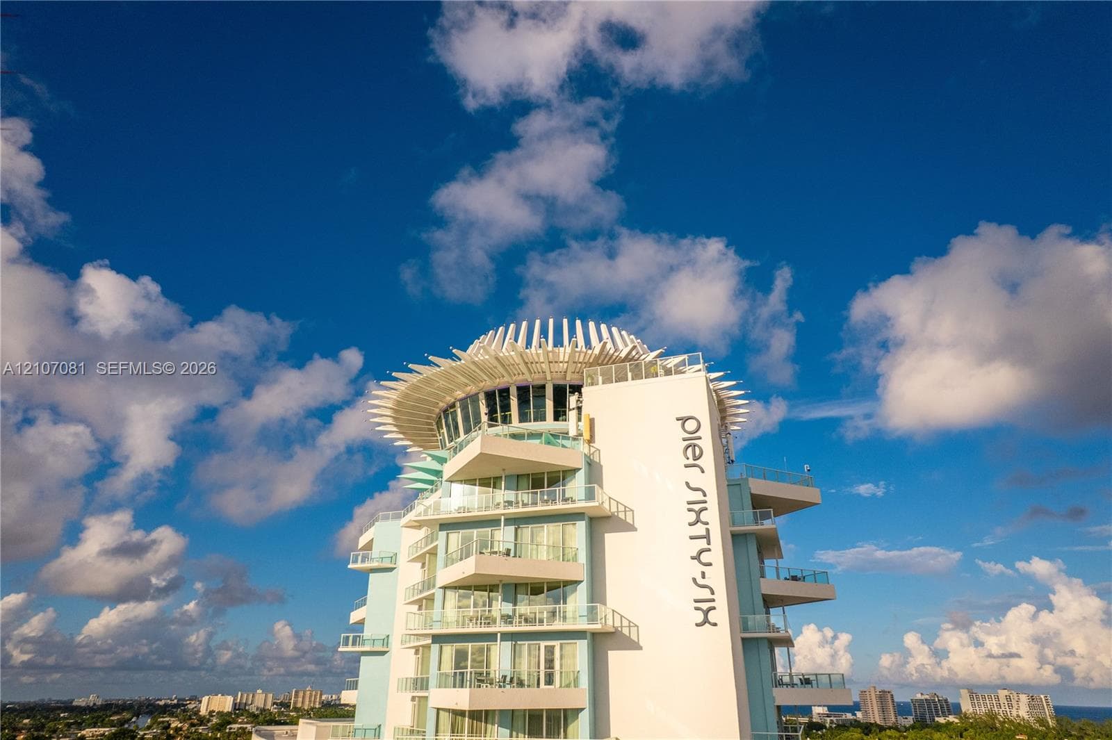 High-rise exterior featuring multi-level wraparound balconies, expansive glass sliding doors, and a distinct crown architectural detail