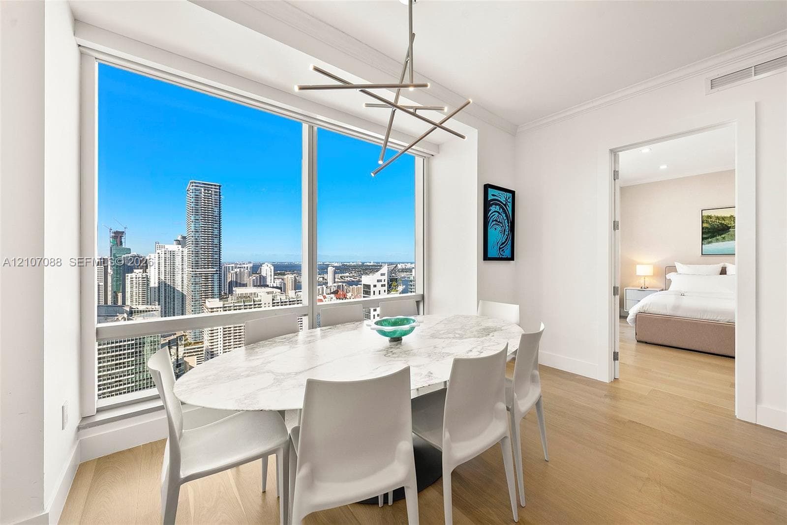 Floor-to-ceiling windows, wood-finish flooring, linear modern chandelier, and neutral wall palette