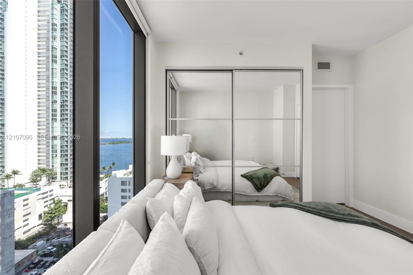 Floor-to-ceiling windows, mirrored sliding-door closet, and neutral interior finishes