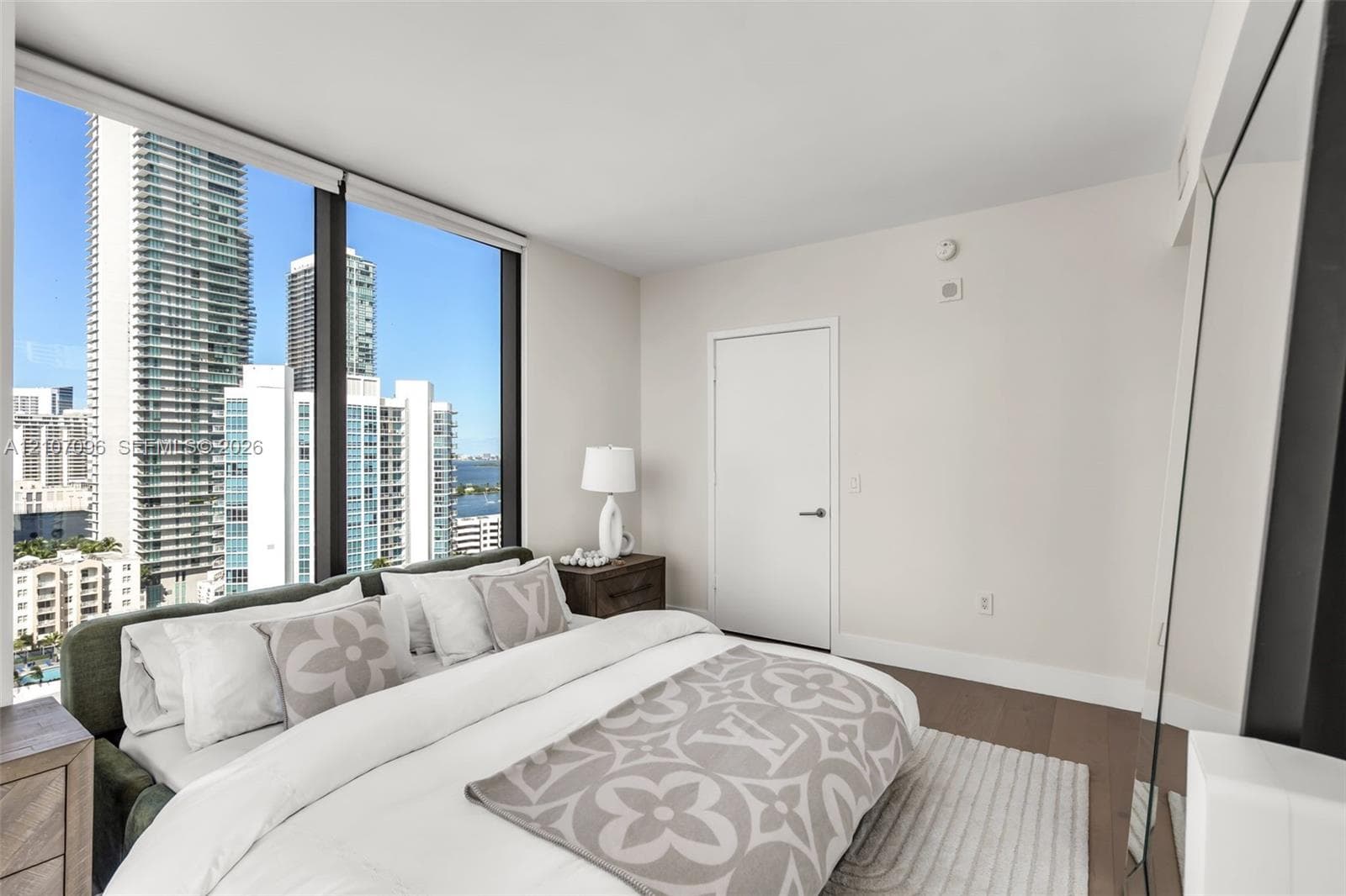 Floor-to-ceiling windows, wood-finish flooring, and expansive urban skyline scenery