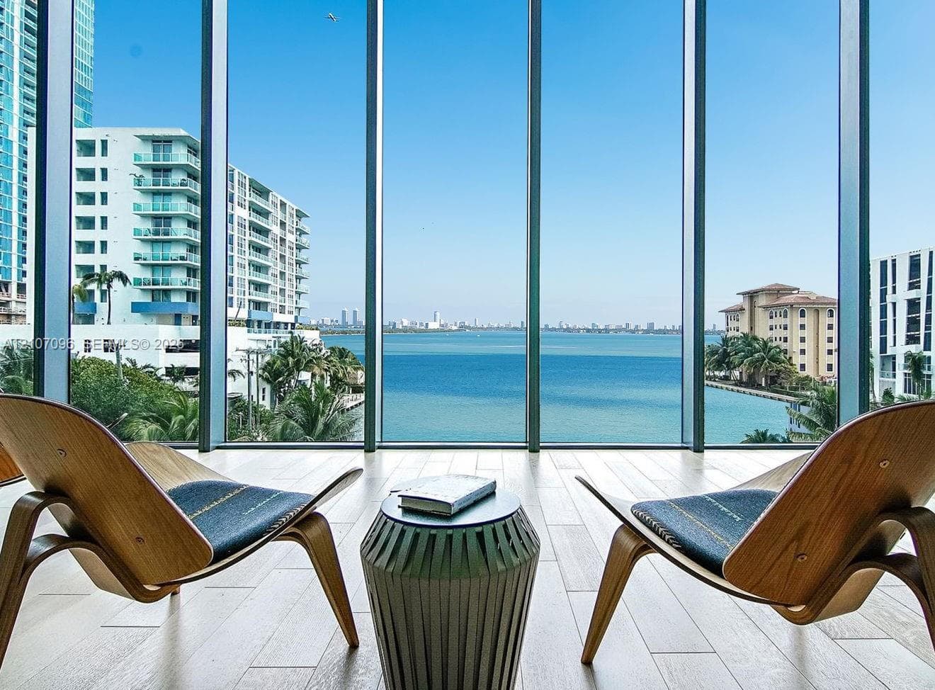 Floor-to-ceiling windows featuring panoramic water and cityscape scenery with wood-finish tile flooring
