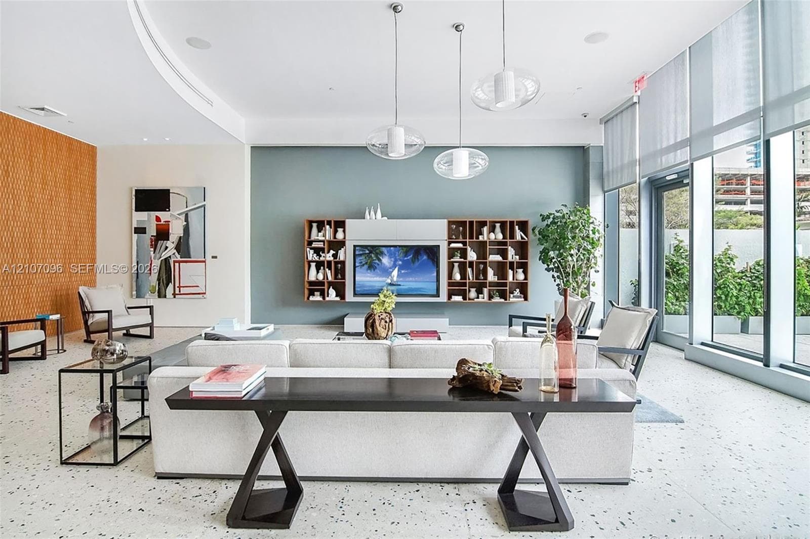 Living area featuring floor-to-ceiling windows, terrazzo flooring, built-in wooden shelving, accent wall, and three glass pendant lights