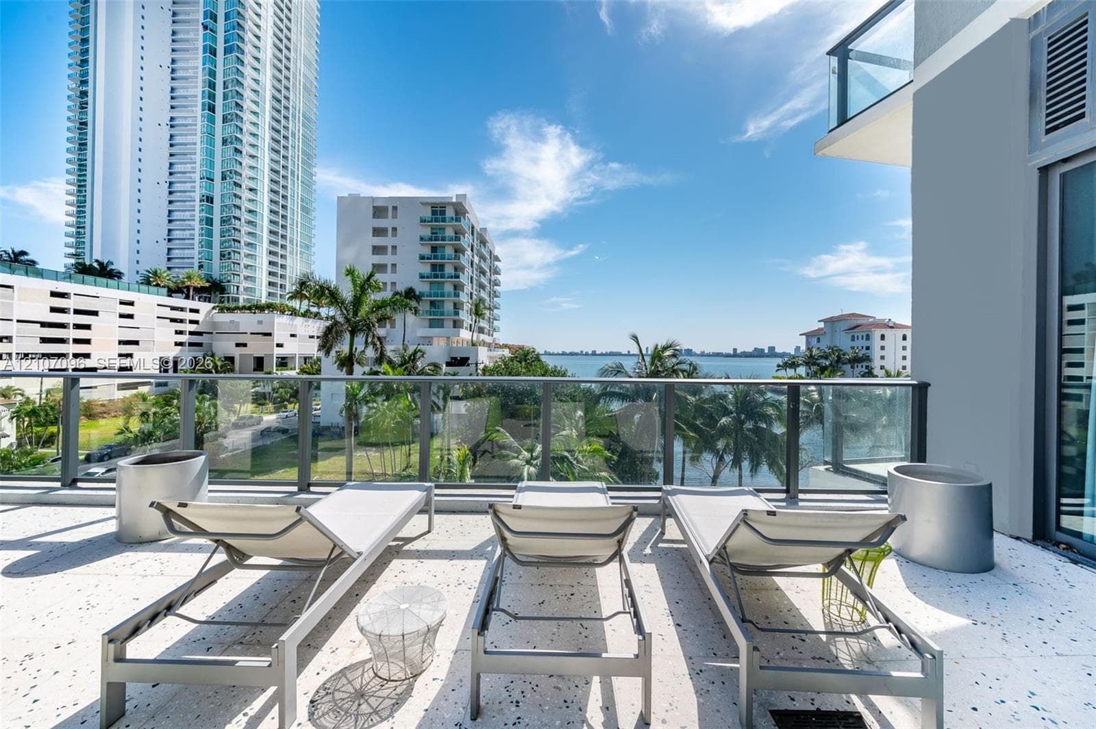 Spacious balcony with terrazzo flooring and glass-panel railing, offering open-air waterfront exposure