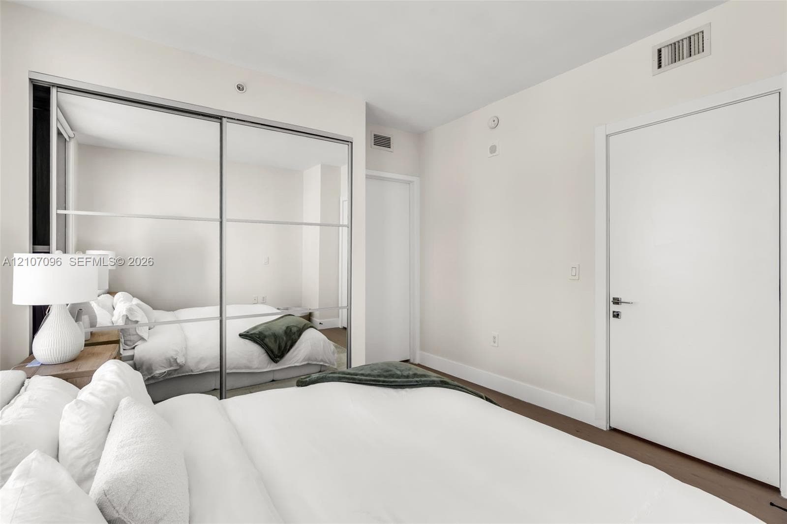 Floor-to-ceiling sliding mirrored closet doors, solid core interior door, and neutral wall finish