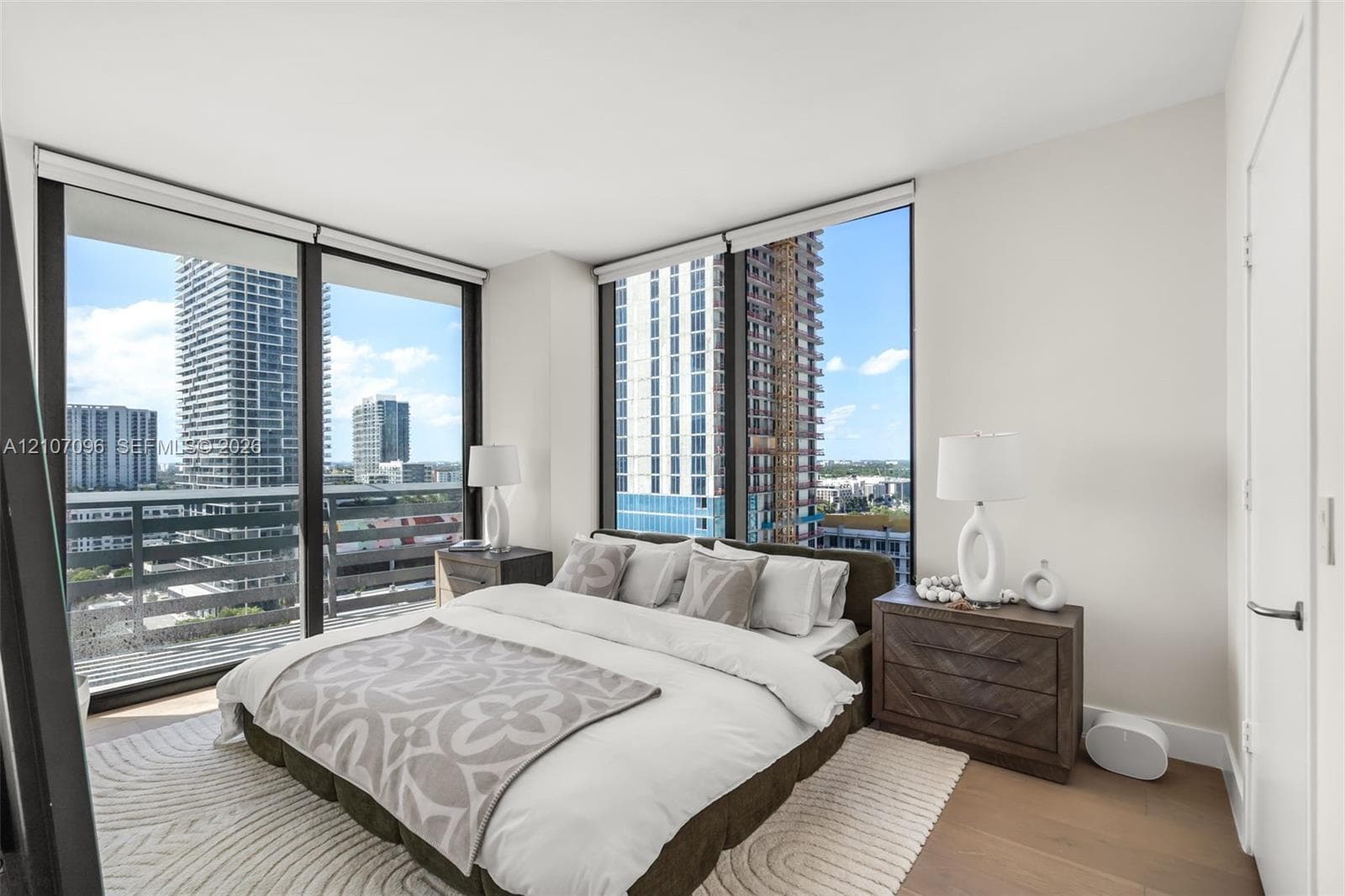 Floor-to-ceiling windows, wood-finish flooring, and metal-framed balcony railing