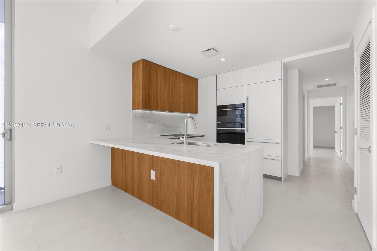 Open interior featuring large-format tile flooring, floor-to-ceiling glass sliding doors, and a curved architectural column