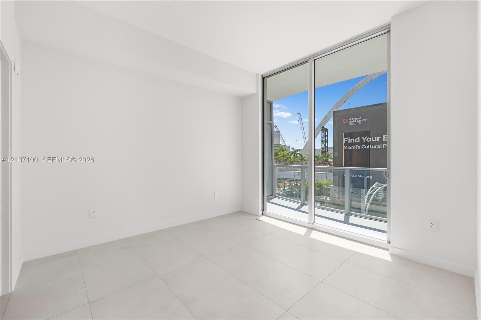 Large-format tile flooring, floor-to-ceiling glass sliding door, and private balcony with metal railing