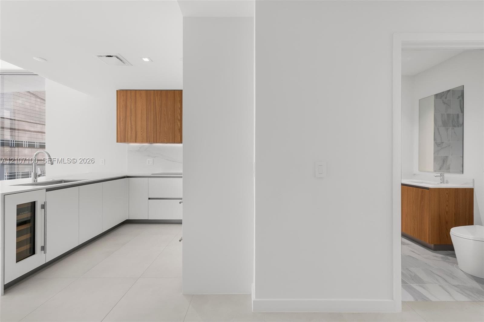Floor-to-ceiling glass sliding doors, large-format tile flooring, a prominent structural column, and access to a perimeter balcony