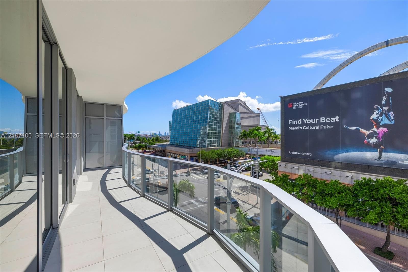 Curved balcony featuring light-toned tile flooring and a glass panel railing