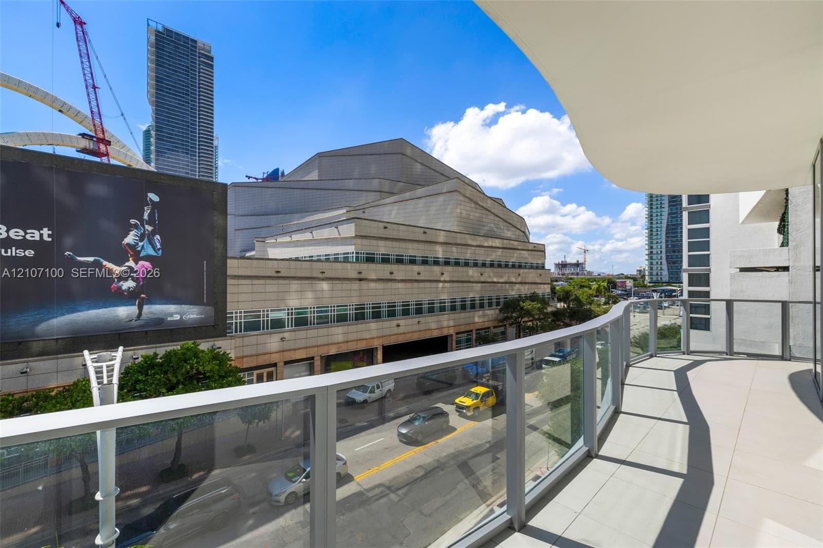 Covered balcony featuring concrete flooring and a glass-paneled railing