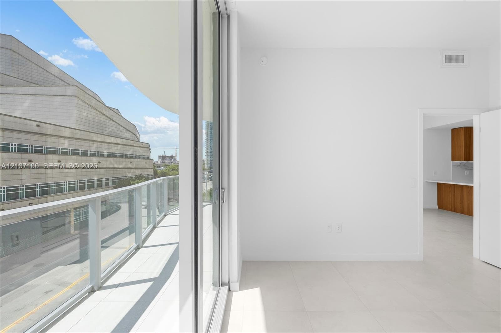 Interior space featuring large-format tile flooring, floor-to-ceiling glass sliding doors, and access to private balcony areas with metal railings