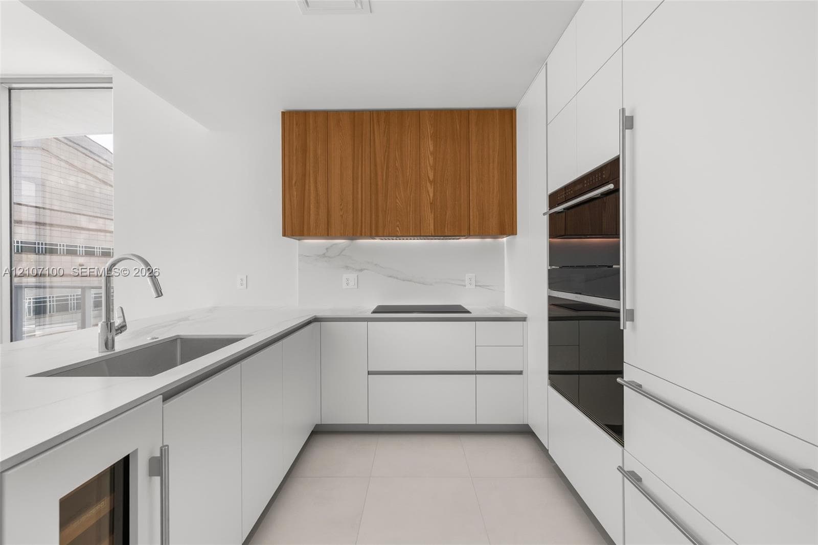 Kitchen featuring matte white and wood-finish cabinetry, stone-surface countertops with a waterfall edge, integrated wine refrigeration, under-cabinet lighting, and floor-to-ceiling windows