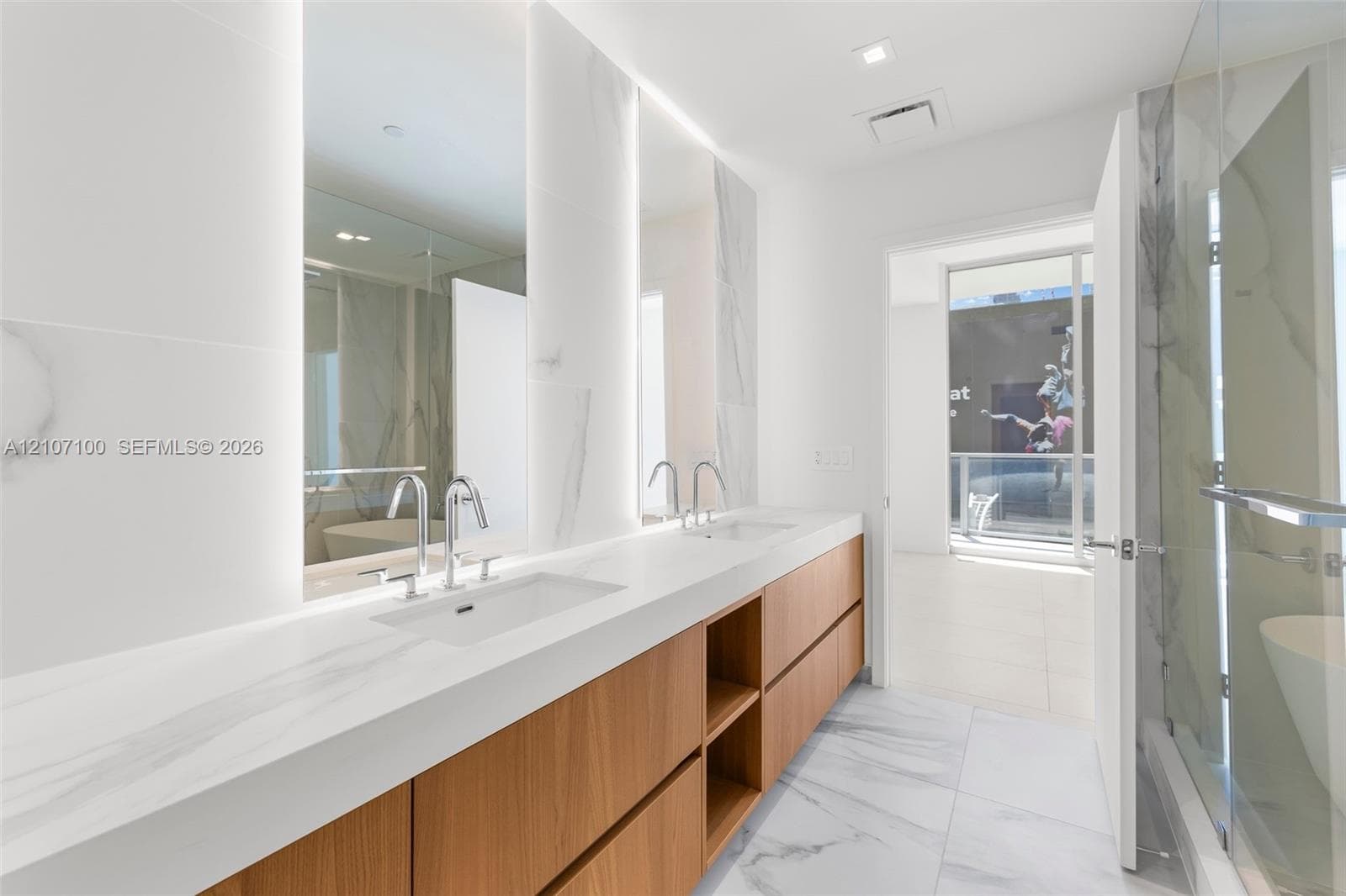 Dual-sink vanity featuring a light-toned countertop, wood-finish cabinetry, floor-to-ceiling veined tile wall treatment, and integrated LED-backlit mirrors