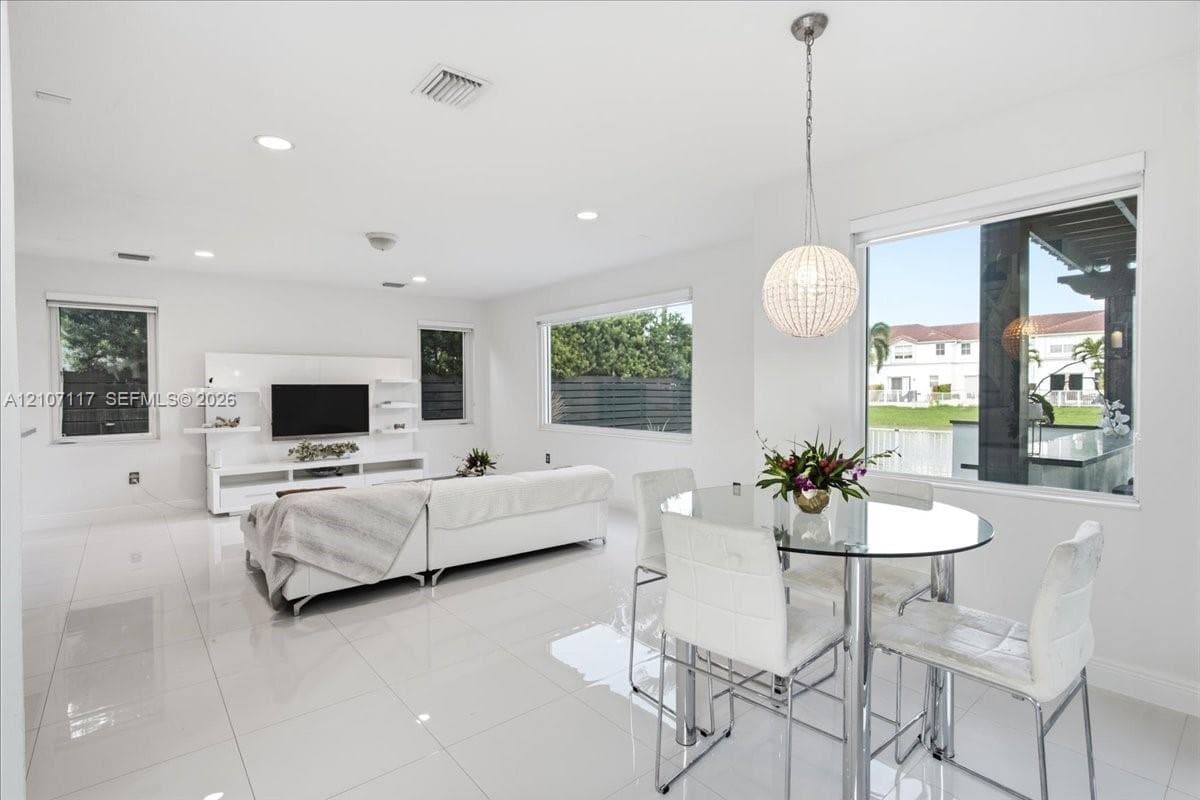 Open-concept interior featuring large-format tile flooring, recessed lighting, a built-in media console, and a spherical crystal pendant light