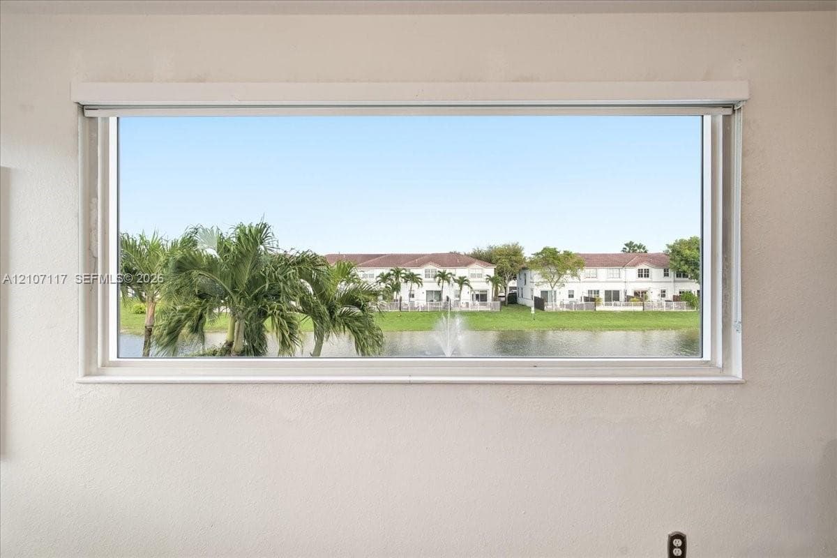 Horizontal window frame featuring a water feature, palm trees, and residential scenery