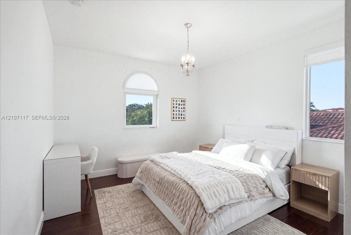 Wood-finish flooring, arched window, and crystal chandelier fixture