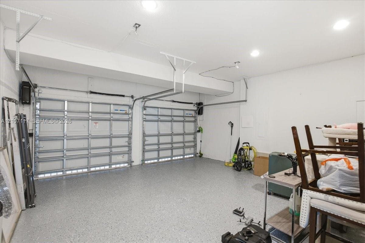 Two-car garage featuring dual overhead metal doors, neutral wall finish, recessed lighting, and durable flecked-epoxy flooring