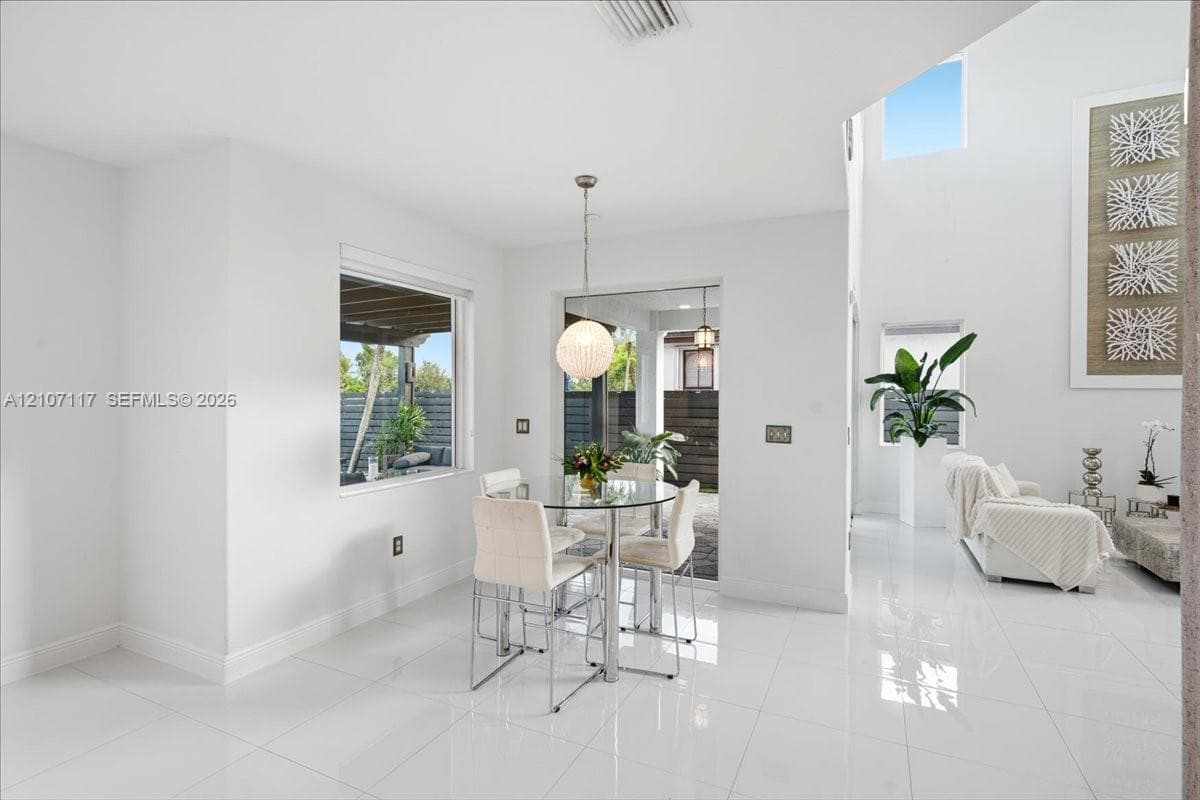 Open-concept space featuring polished tile flooring, soaring vaulted ceilings, expansive windows, and a modern spherical pendant light fixture