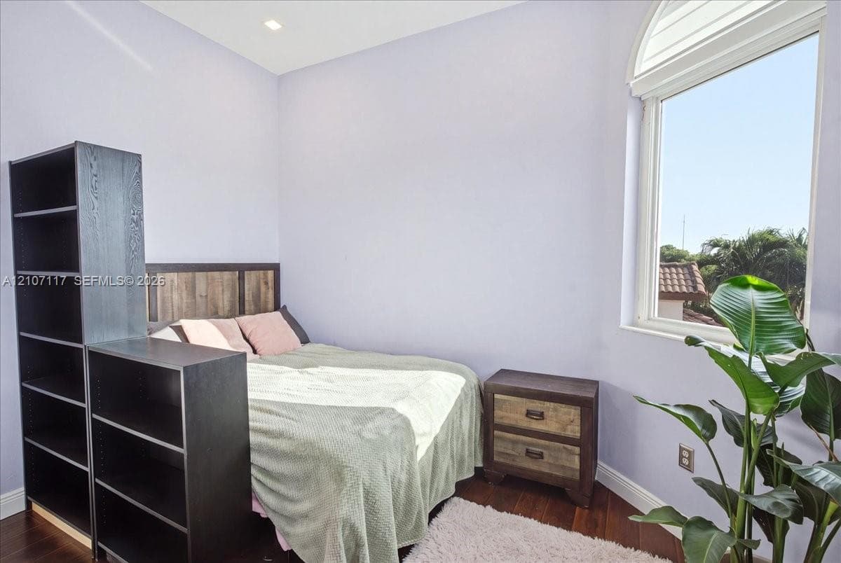 Room featuring dark wood-finish flooring, recessed ceiling lighting, and an arched window