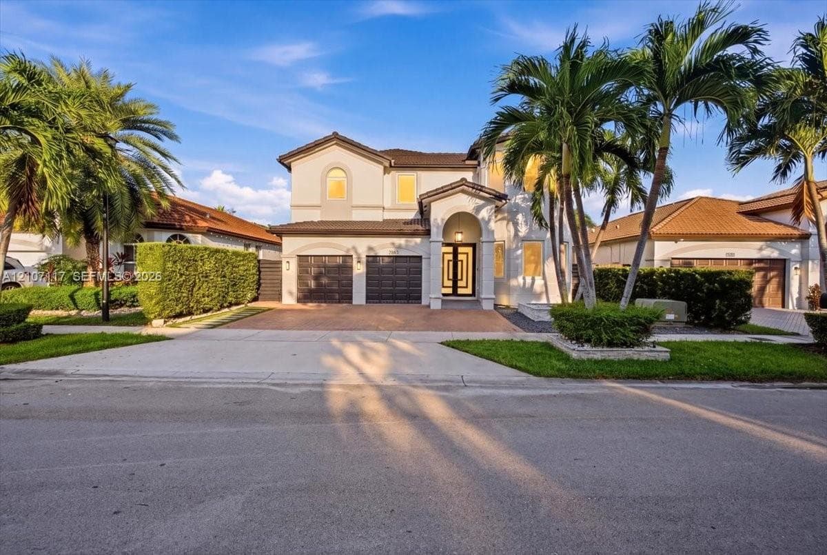 Two-story residence featuring a tile roof, stucco exterior, covered entryway, and three-car garage with paneled doors