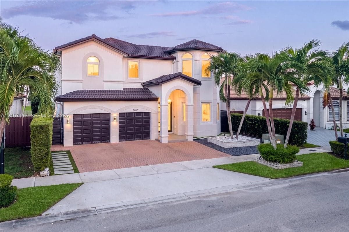 Two-story Mediterranean-style exterior featuring a tile roof, arched entryway, stucco facade, and an attached two-car garage with a paved driveway