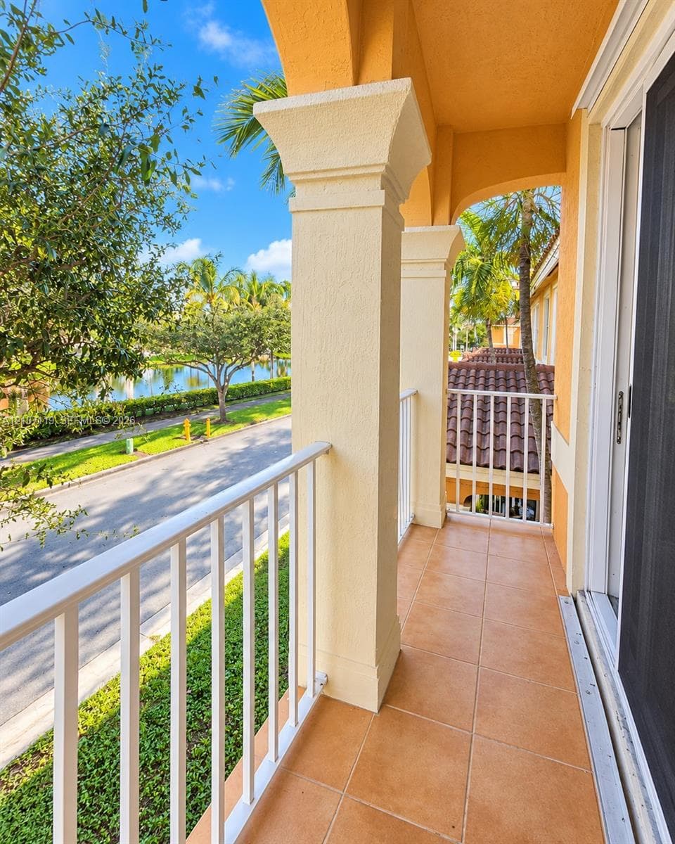 Covered balcony featuring square support columns, ceramic tile flooring, and white metal railing