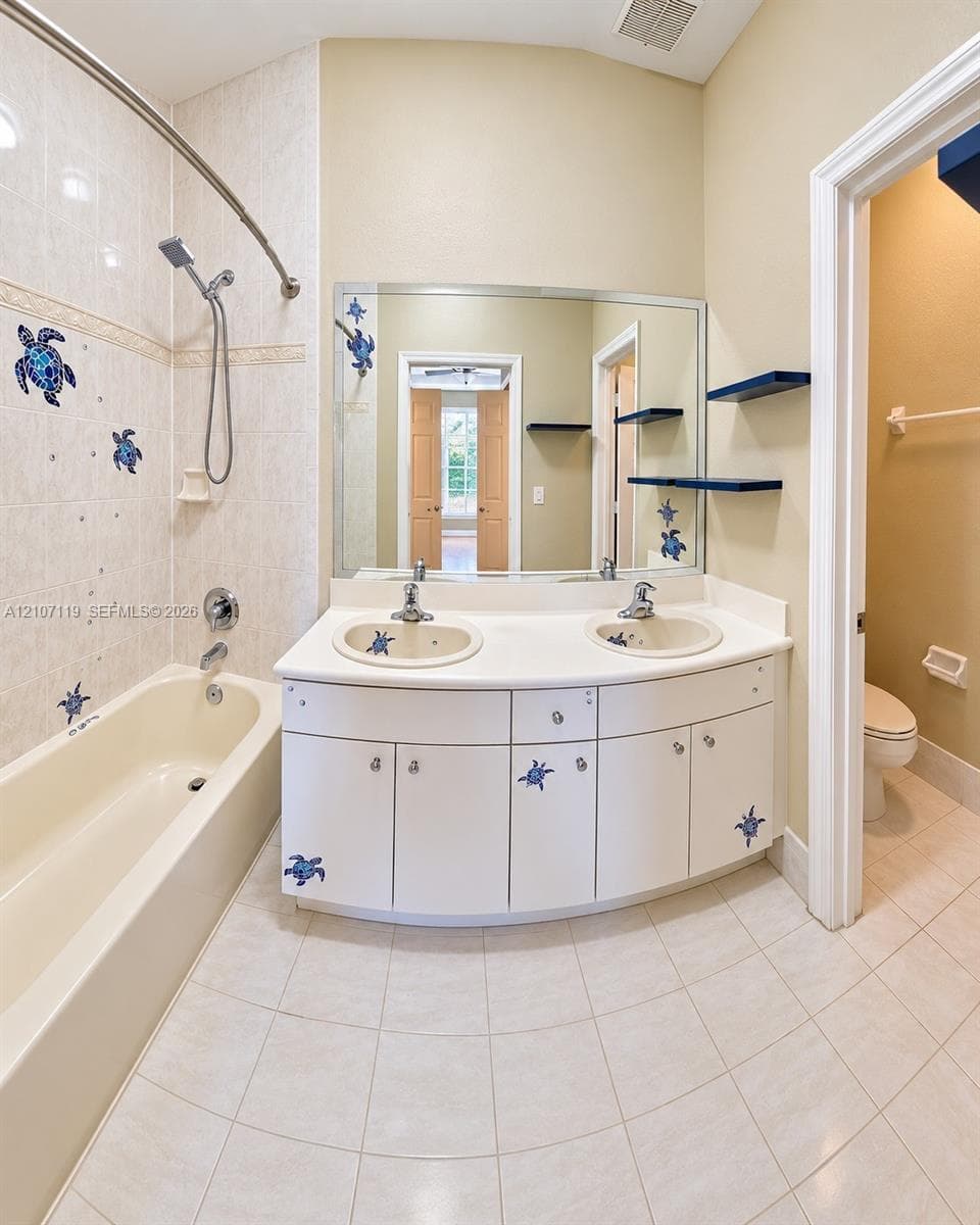 Double vanity featuring white cabinetry, integrated sinks, and a solid-surface countertop with an expansive wall-mounted mirror