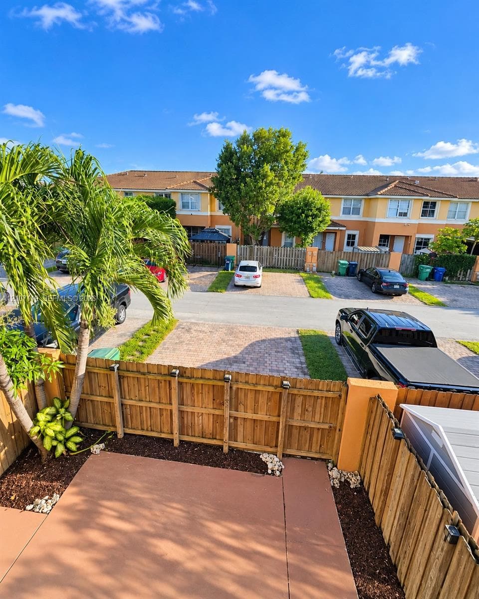 Private concrete patio featuring wood privacy fencing, mature palm trees, and mulch border landscaping