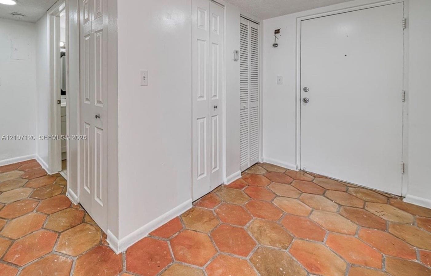 Entryway featuring hexagonal terracotta flooring, multiple paneled doors, and louvered closet doors