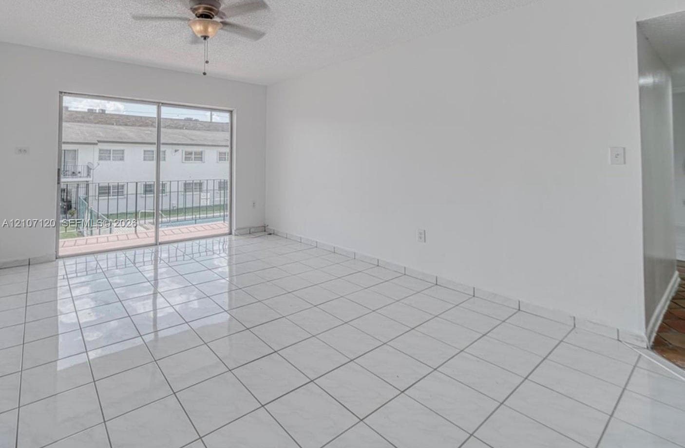 Interior space featuring large-format ceramic tile flooring, a ceiling fan with integrated lighting, and sliding glass doors with balcony access