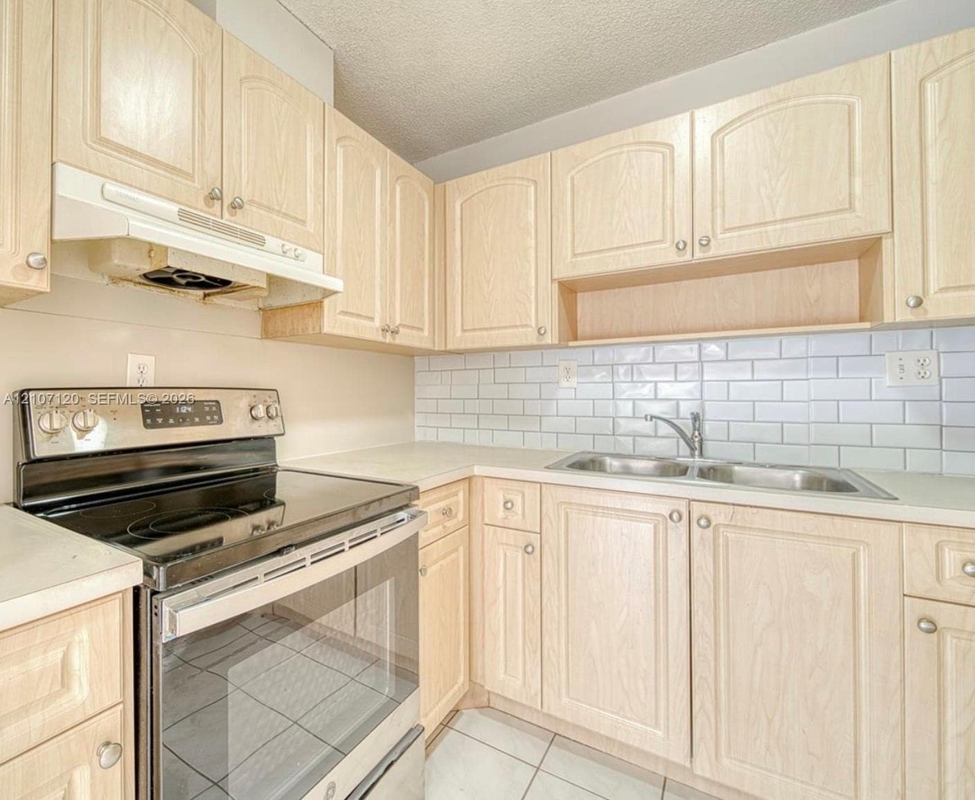 Kitchen featuring light-finish cabinetry, subway tile backsplash, stainless steel range with overhead hood, and double-basin stainless steel sink