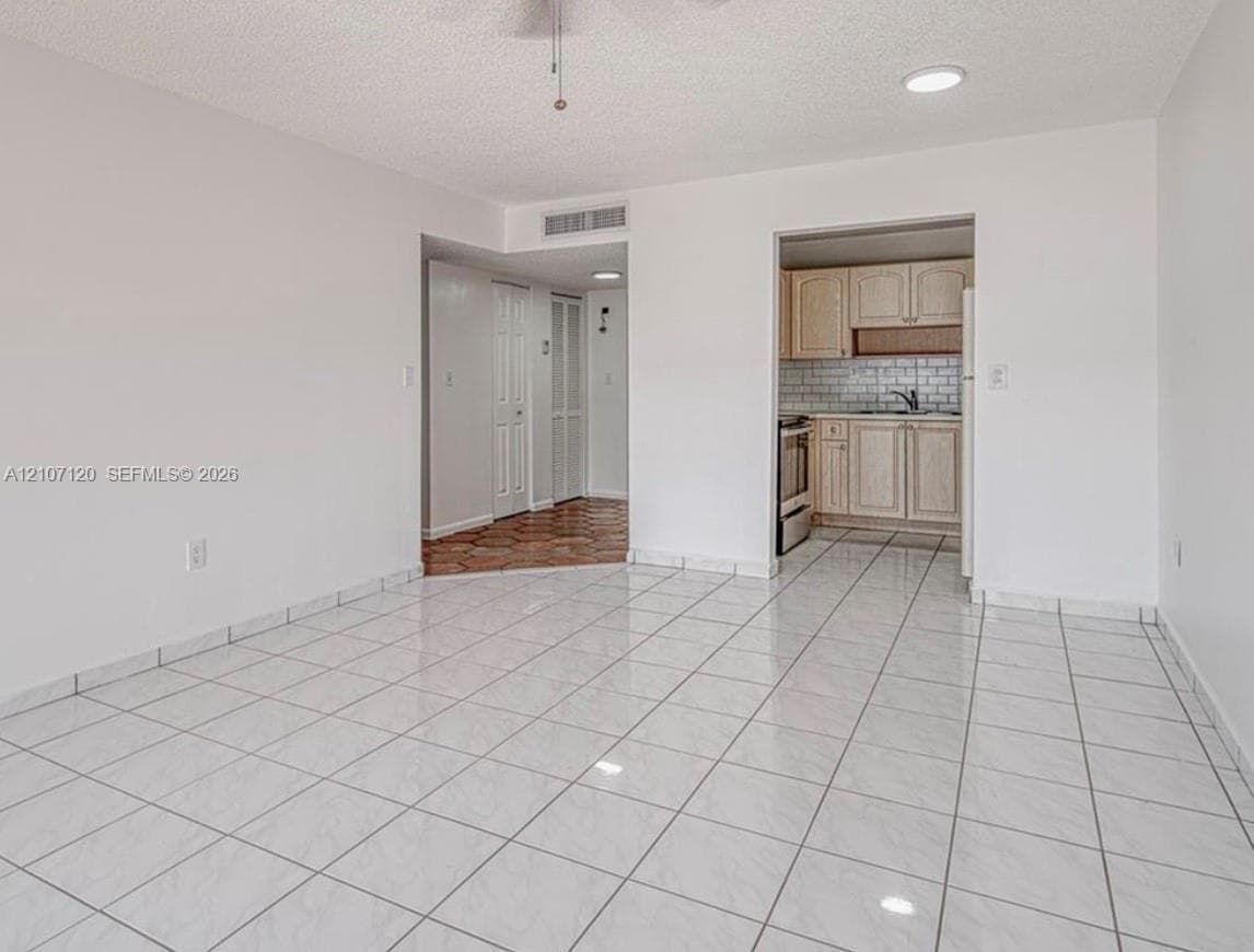 Open floor plan featuring large-format ceramic tile flooring, recessed lighting, and a kitchen equipped with wood cabinetry and a subway tile backsplash