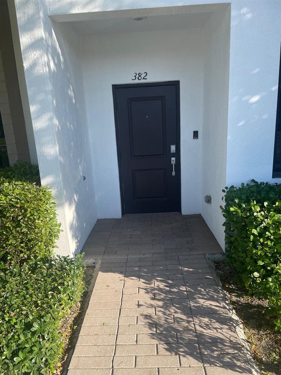 Covered entryway featuring a recessed front door and paver walkway