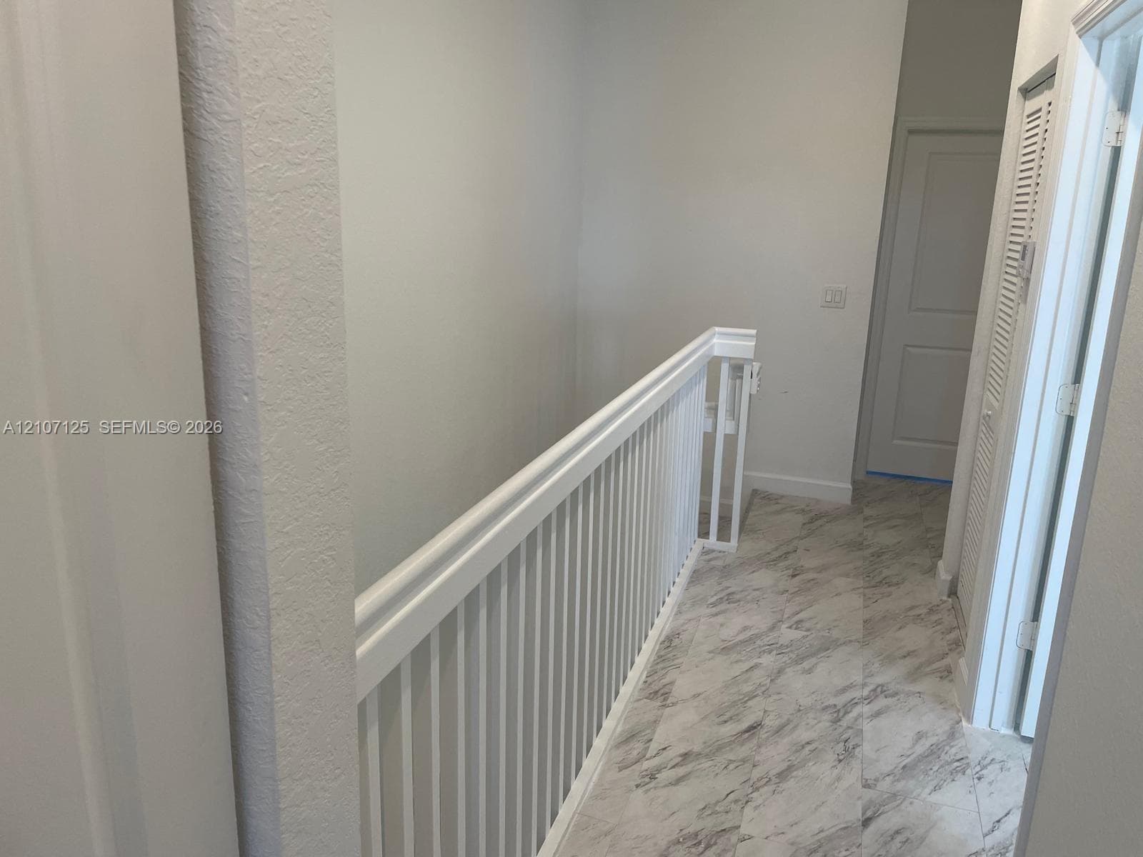 White wooden railing with vertical balusters, stone-finish flooring, and paneled doors