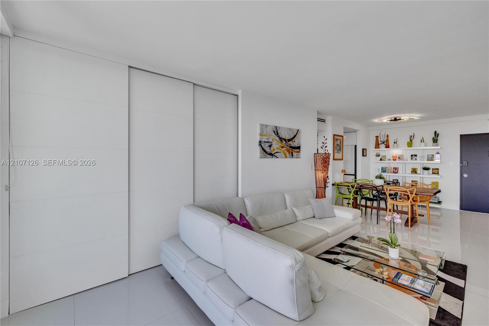 Large-format white tile flooring, floor-to-ceiling white sliding panel doors, and built-in wall shelving