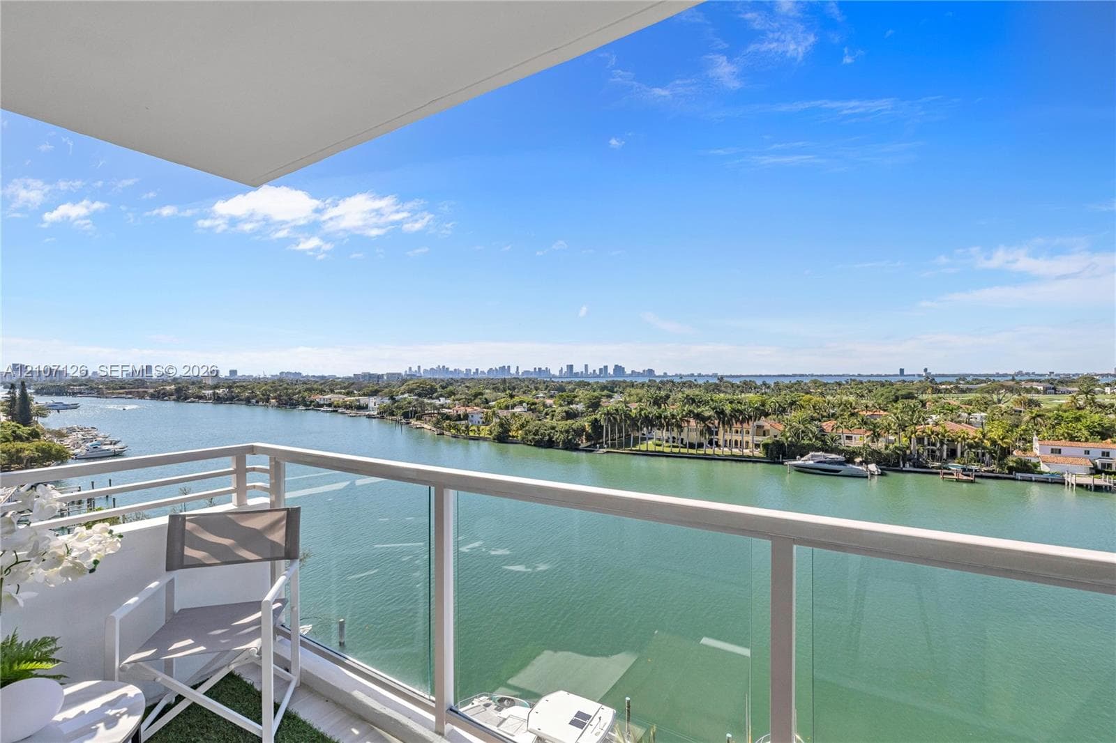 Private balcony featuring a glass panel railing and open-air design with expansive water and city skyline surroundings