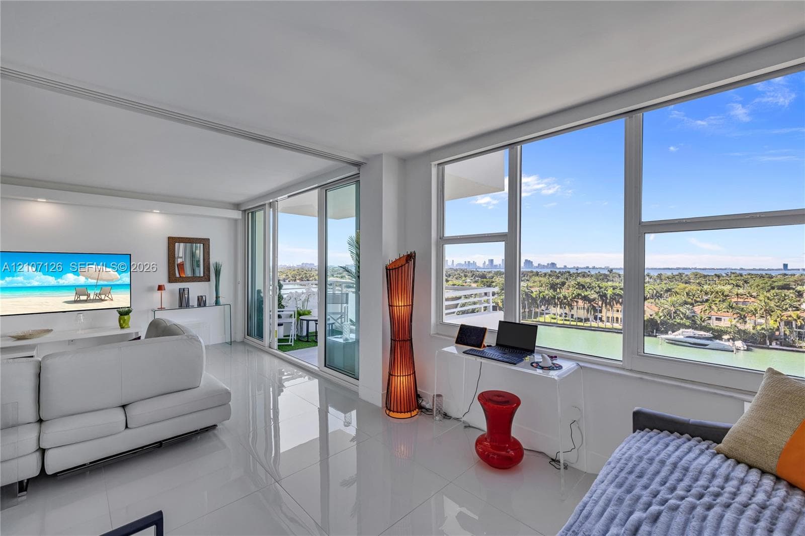 Expansive living area featuring large-format tile flooring, floor-to-ceiling windows, and sliding glass doors opening to a balcony