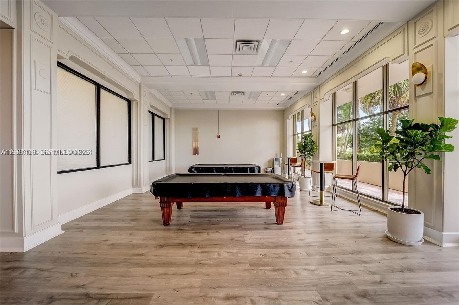 Spacious room featuring wood-finish flooring, decorative wall molding, recessed ceiling lighting, and floor-to-ceiling windows