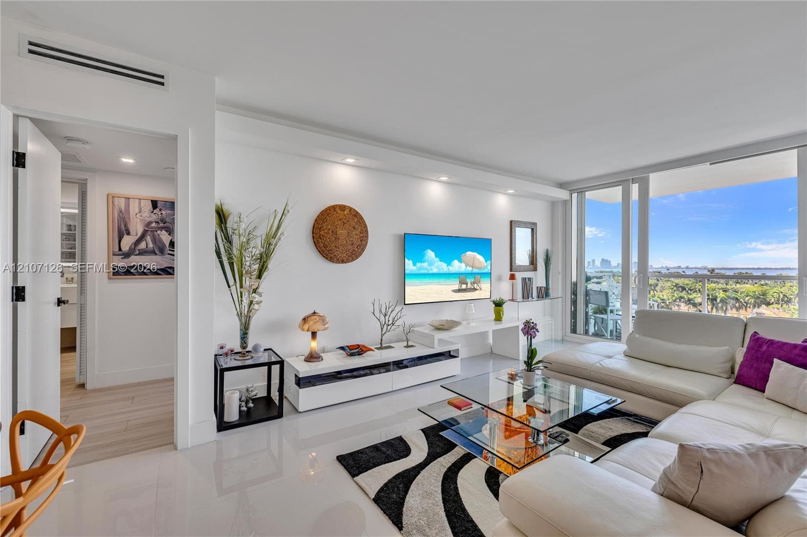 Living area featuring large-format tile flooring, recessed ceiling lighting, a built-in media console, and floor-to-ceiling glass sliding doors opening to a balcony