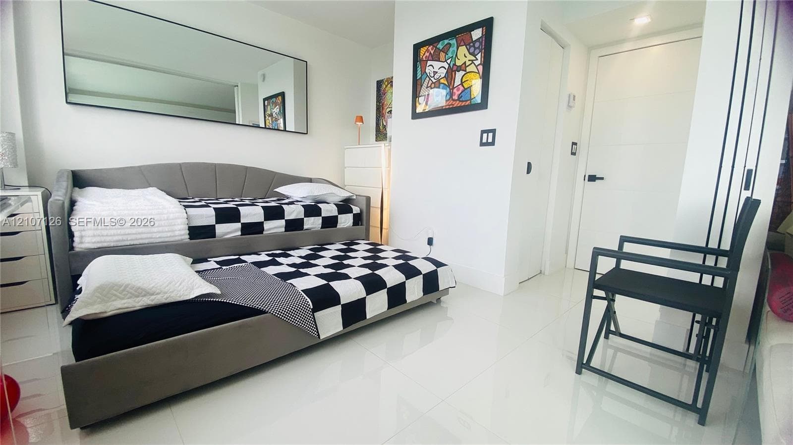 High-gloss tile flooring, large wall-mounted mirror, and multi-panel interior door with matte black hardware
